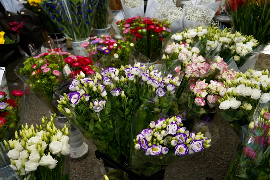 A vibrant display of fresh flower bouquets arranged on a market table, featuring an assortment of blooms including purple and white irises with ruffled petals, delicate white lisianthus, pink and whit